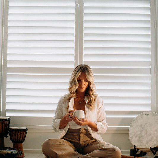 Woman enjoying a serene tea ceremony with a cup of High Frequency Tea, surrounded by a peaceful setting